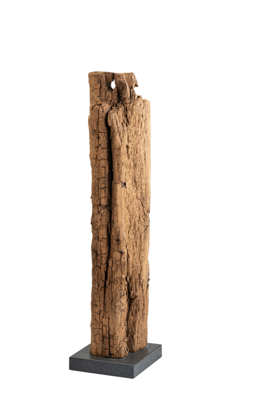 Eine Eichenholz-Skulptur, die auf einem steinernen Sockel steht. Die Skulptur zeigt eine abstrakte Form, die aus dem Eichenholz geschnitzt wurde. Die natürliche Maserung des Holzes ist sichtbar und verleiht der Skulptur eine warme und organische Ästhetik. Die Skulptur steht stabil auf einem massiven Steinsockel, der ihr eine solide Basis verleiht. Die Kombination aus Holz und Stein schafft eine harmonische Verbindung von Natur und Handwerkskunst.